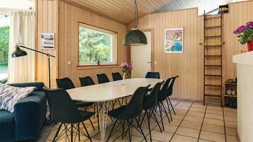 Un interior de madera con una mesa de comedor, sillas, un sofá, una lámpara y una escalera.