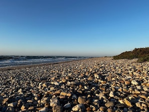 A rocky beach with waves, a clear sky, and a distant shoreline. - 4 Star Holiday Home in Gilleleje (Gilleleje)
