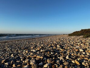 A rocky beach with waves, a clear sky, and a distant shoreline. - 4 Star Holiday Home in Gilleleje (Gilleleje)