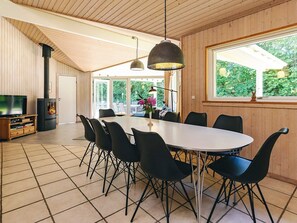 A dining area with a large table, black chairs, a television, and a fireplace. - 4 Star Holiday Home in Gilleleje (Gilleleje)