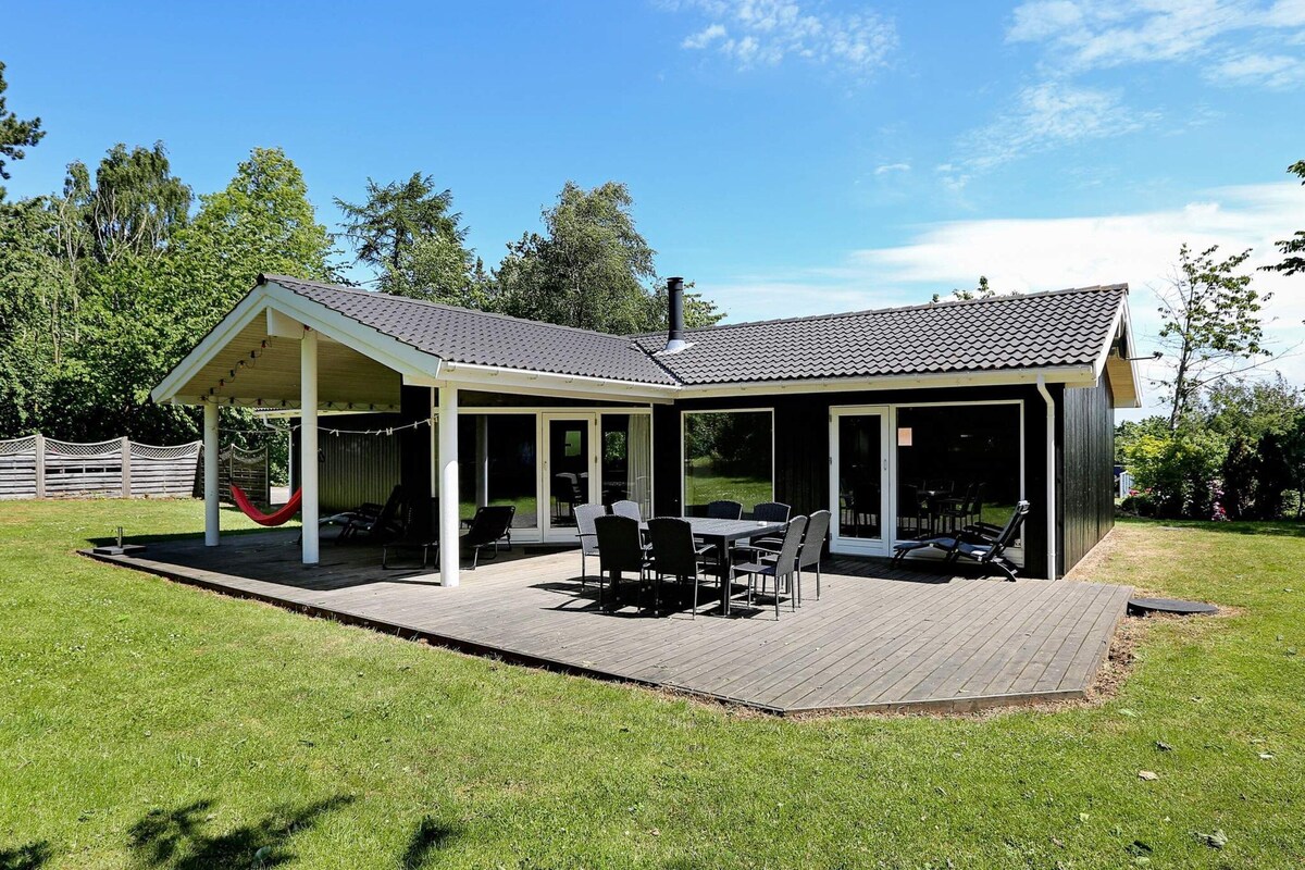 A covered patio with a table and chairs, a hammock, and a grill area.