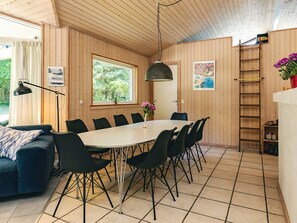 Un interior de madera con una mesa de comedor, sillas, un sofá, una lámpara y una escalera.