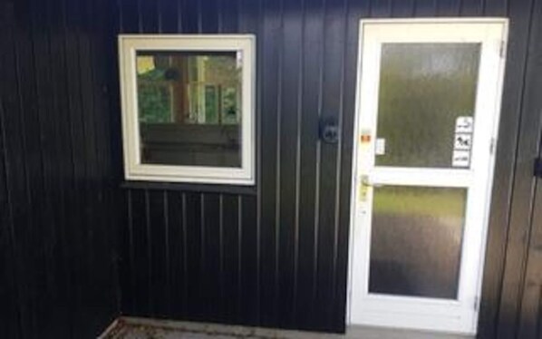 A dark-colored exterior wall with a white-framed window and a glass door with a metal handle.