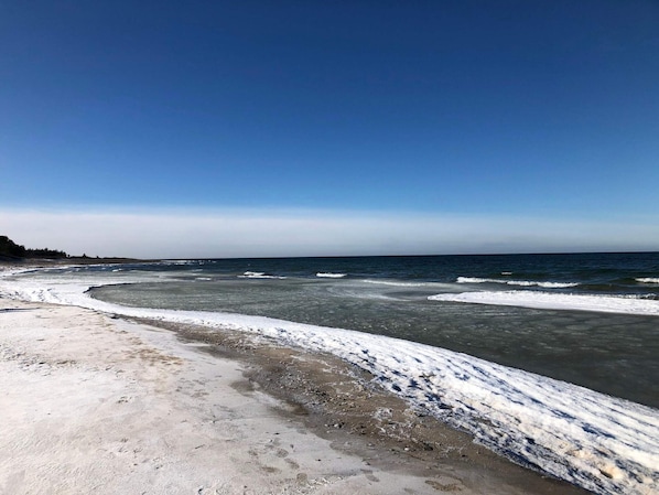Une plage avec des formations de glace et des vagues.