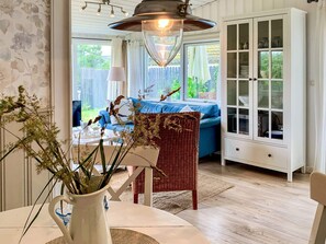 A dining area with a table, chairs, a wicker basket, a cabinet with glass doors, and a hanging light fixture. - 4 Star Holiday Home in Blokhus (Blokhus)