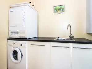 A compact kitchen with a washing machine, a sink, and a small decorative item on the wall. - 5 Star Holiday Home in Hovborg (Hovborg)