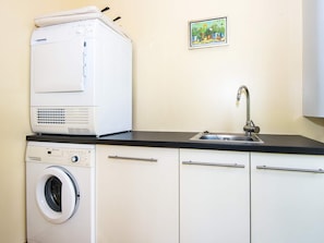 A compact kitchen with a washing machine, a sink, and a small potted plant on the wall. - 5 Star Holiday Home in Hovborg (Hovborg)