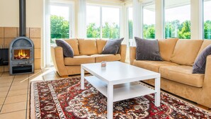 A living room with a sofa set, a white coffee table, a patterned rug, and a wood-burning stove. - 5 Star Holiday Home in Hovborg (Hovborg)
