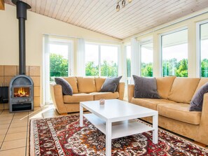 A living room with a sofa set, a white coffee table, a patterned rug, and a wood-burning stove. - 5 Star Holiday Home in Hovborg (Hovborg)