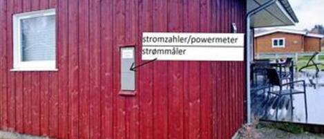 A red building with a window and a sign indicating a power meter.