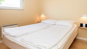 A bedroom with a bed, two bedside lamps, a window, and a radiator. - 5 Star Holiday Home in Hovborg (Hovborg)