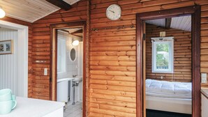 A wooden cabin interior with a bathroom, a bed, and a dining area. - 4 Star Holiday Home in Blavand (Blavand)