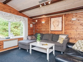 Interior acogedor de una cabaña con un sofá, una mesita y una ventana con vista a la vegetación.