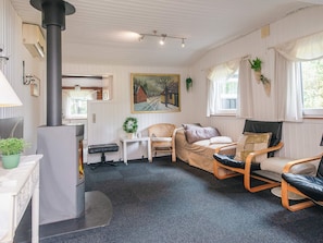 A cozy room with a fireplace, a sofa, two chairs, a small table, and a painting on the wall. - 4 Star Holiday Home in Blavand (Blavand)