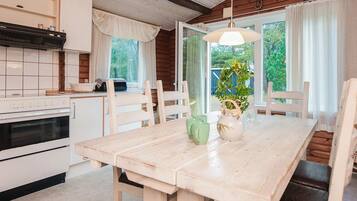 Una cocina con estufa blanca, armarios y ventana con cortinas.