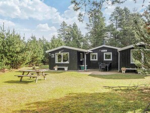 A cabin with a picnic table and outdoor seating area. - 4 Star Holiday Home in Blavand (Blavand)