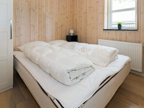 A single bed with white bedding in a room with wooden panel walls and a window with a plant on the sill. - 5 Star Holiday Home in Hadsund (Hadsund)