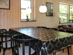 A dining area with a long table, chairs, and a wall-mounted menu. - 5 Star Holiday Home in Hadsund (Hadsund)