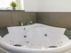 A white bathtub with a modern faucet and controls, set against a tiled wall.