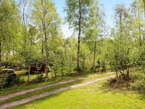 A forested area with a dirt path and a red structure. - 5 Star Holiday Home in Hadsund (Hadsund)