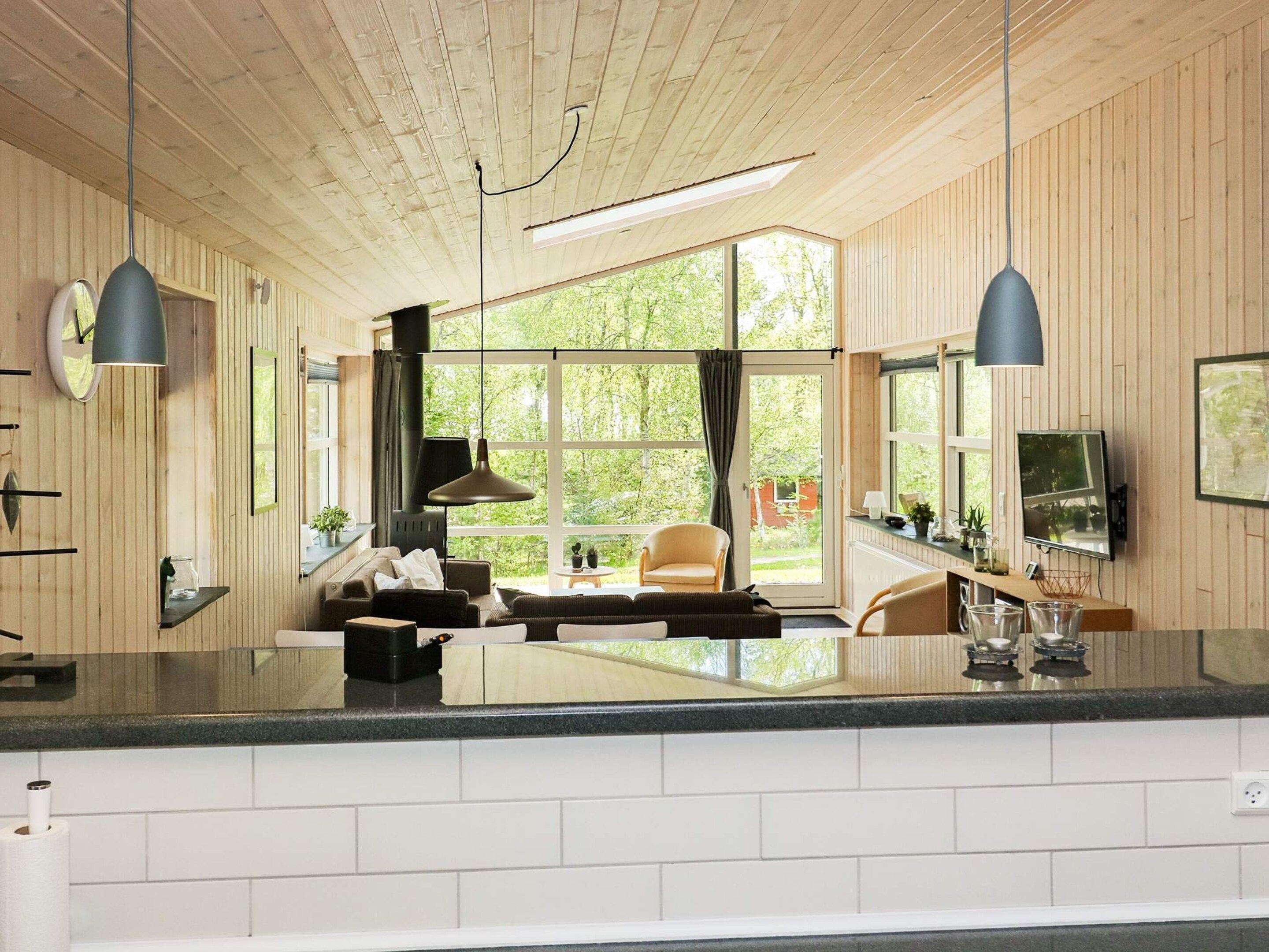 A modern interior with a kitchen area, dining space, and a large window providing a view of the outdoors.
