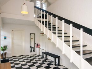 A staircase with white railings and dark steps, a checkered floor, a bench, a hanging mirror, and a pendant light. - Luxurious Holiday Home in Jutland with Hot Tub (Aabenraa)