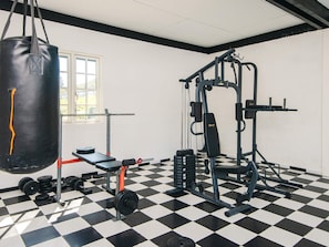 Ein Fitnessstudio mit Schachbrettmuster-Bodenbelag, Gewichthebequipment und einem Schlagball.