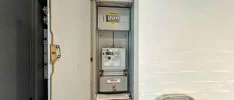 An electrical panel with a label, a door, and a wall-mounted unit.