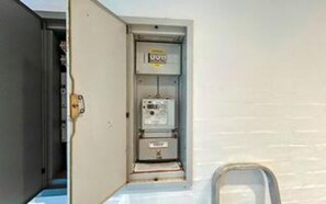 An electrical panel with a label, a door, and a wall-mounted unit.
