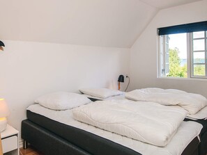 A bedroom with a bed, a lamp, and a window with a view. - Luxurious Holiday Home in Jutland with Hot Tub (Aabenraa)