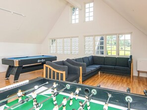 Ein Zimmer mit Tischfußball, Billardtisch und einem Ecksofa.