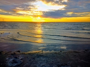 Ein Strand mit Wellen und einem Sonnenuntergang.