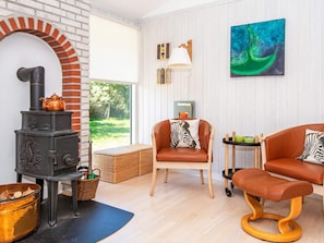 A cozy living room with a fireplace, two leather sofas, a wicker basket, and a painting on the wall.