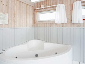 Moderni kylpyhuone, jossa on erillinen kylpyamme, puupaneloidut seinät, ikkuna ja pyyhekoukku.