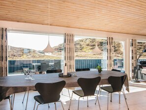 A modern dining area with a large table, chairs, and a view of the outdoors.