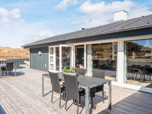 Une terrasse dotée de mobilier d’extérieur, d’une porte-fenêtre et offrant une vue sur le paysage environnant.