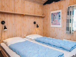 A room with wooden walls, a bed with blue bedding, two wall-mounted lamps, and a framed picture on the wall. - 10 Person Holiday Home in Fano (Fano)