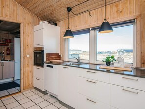 A modern kitchen with wooden walls, a large window, and a view of the landscape. - 10 Person Holiday Home in Fano (Fano)