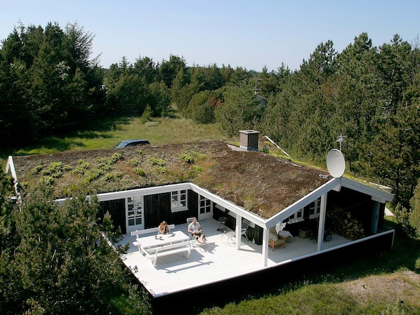 A house with a green roof, a deck, and a satellite dish.