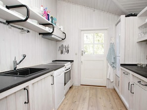 A kitchen with white cabinetry, a black countertop, a stove, and a sink.