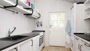 A kitchen with white cabinetry, a black countertop, a stove, and a sink. - 6 Person Holiday Home in Albaek (Aalbaek)