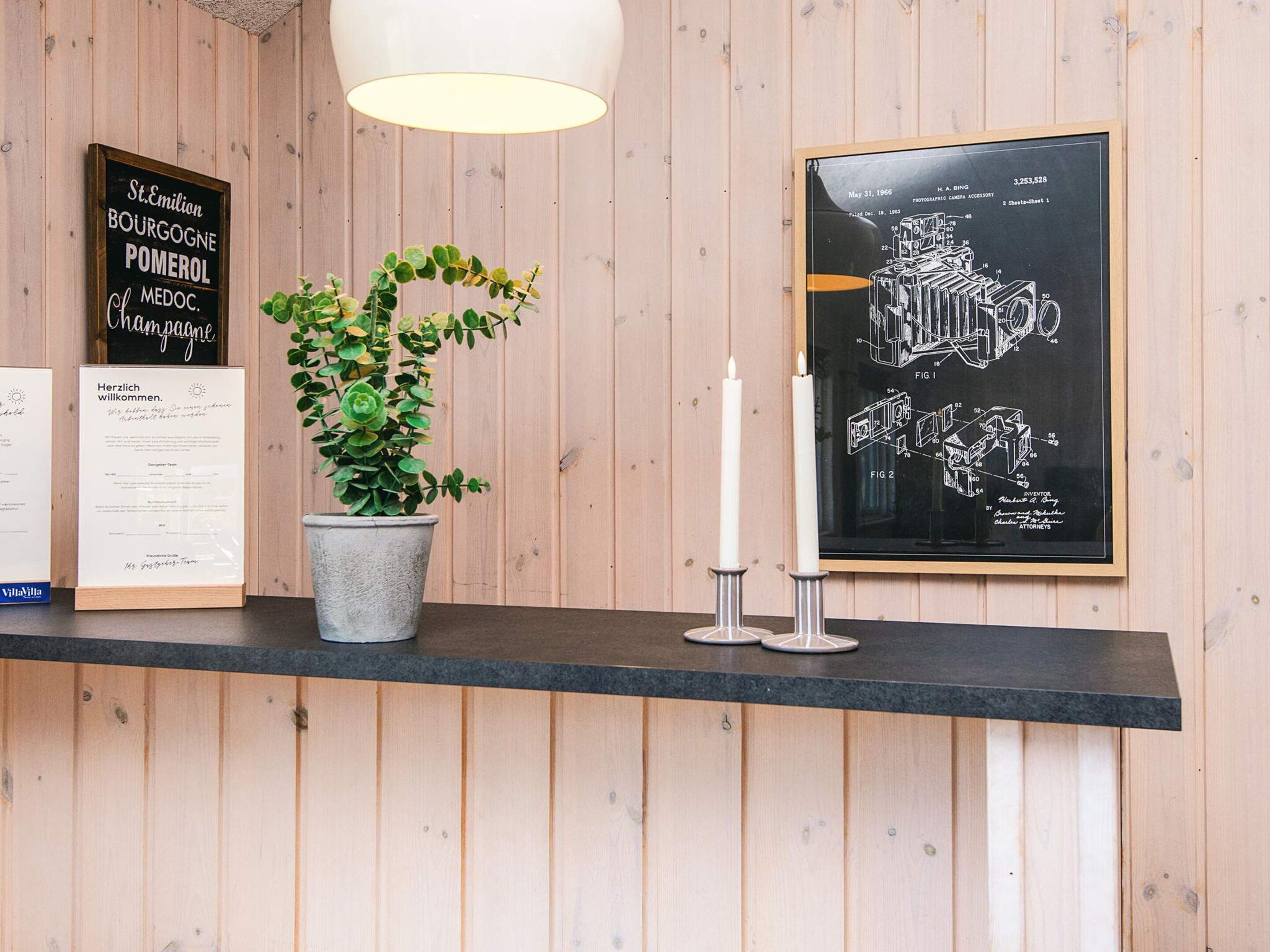 A reception desk with a potted plant, framed patent drawings, and a sign with French text.