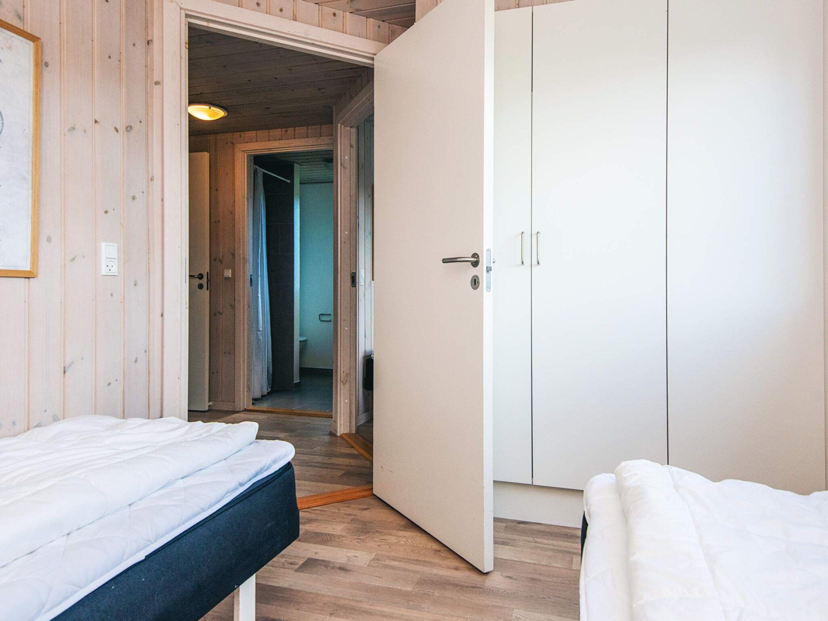 Une chambre à coucher avec un lit, une armoire et une salle de bain visible à travers une porte ouverte.