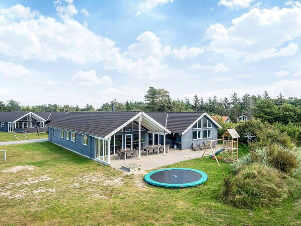 A row of blue buildings with a covered patio area and a trampoline in the foreground. - 5 Star Holiday Home in Blavand (Blavand)