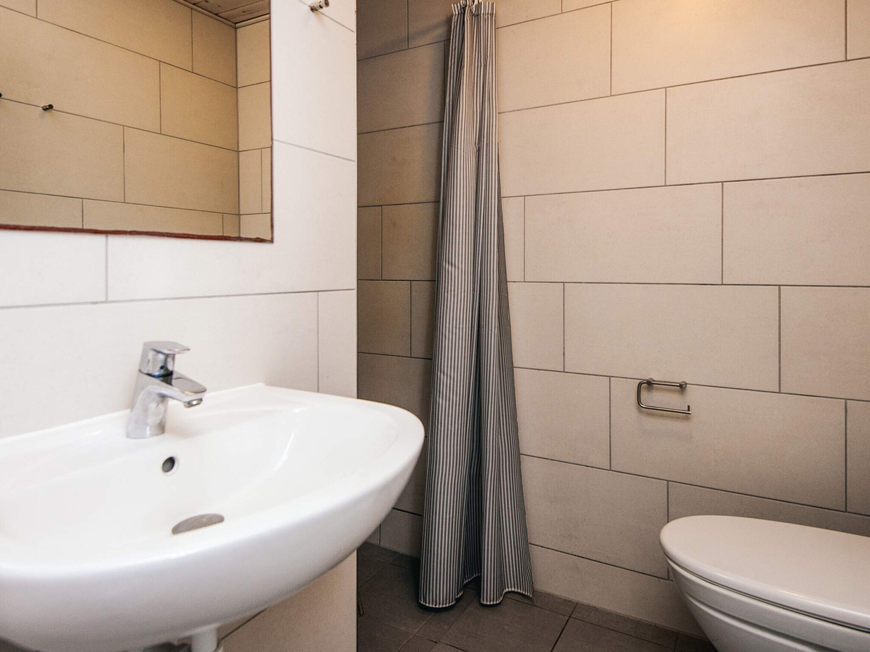 A bathroom with a white sink, a toilet, and a shower curtain.