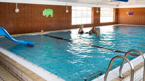 An indoor swimming pool with a blue slide, a lifeguard stand, and a brick wall with a hippopotamus decoration. - 6 Person Holiday Home in Romo (Rømø)