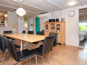 A dining area with a wooden table and black chairs, a wooden cabinet with dishes, and a clock on the wall. - 12 Person Holiday Home in Nordborg (Nordborg)