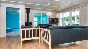 Ein modernes Wohnzimmer mit Holzboden, einer schwarzen Couch, einem Holztisch, einem Fernseher und einem Kamin.