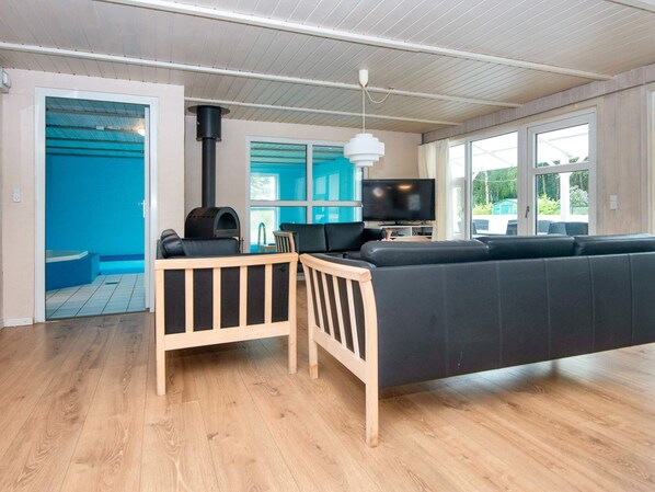 A modern living room with a wooden floor, a black sofa, a wooden table, and a television.