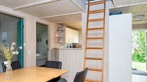Eine moderne Küche mit weißen Schränken, einem Holztisch und einer Leiter.